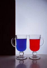 silhouettes of two glasses on a black and white background. Blue and red liquid