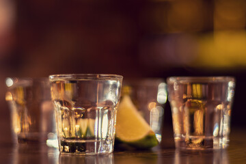 glass of vodka shots on wooden table close up