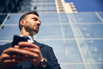 Young brunette man staying outside with smartphone
