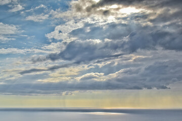 Naklejka premium Sun shines through rain clouds over Tasman sea horizon