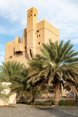 Fototapeta na wymiar View at Fort Fiqain behind palm trees in Manah, Oman