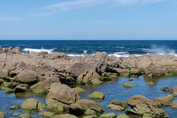 Fototapeta na wymiar ocean wave splash on rocks on the coast on a sunny day with blue sky