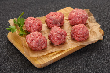 Raw meatball over wooden background