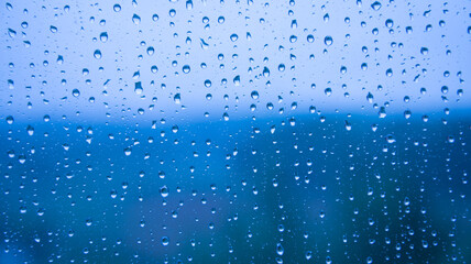 Naklejka na ściany i meble raindrops on the glass close-up. Background texture. Bad weather. Blue cold shades.