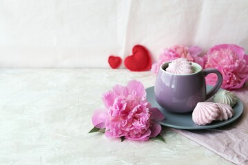 Fototapeta na wymiar Cup of coffee with meringues, pink peony flowers, hearts on a light background, romantic breakfast concept