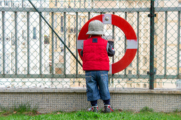 Little boy stay near mesh fence