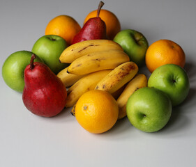 red pears, green apples, tangerines and bananas on a white background