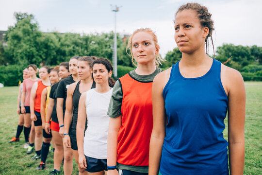 A line of women wearing sports vests in a training field during rugby training.