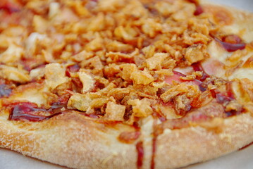 Rustic pizza with bacon, cheese, smoked home-made sausage, paprika, fried onions and ketchup