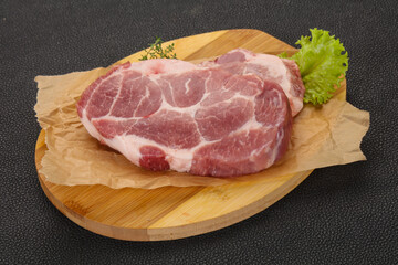 Raw pork steak over wooden board