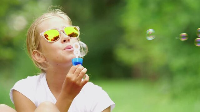 Girl playing with soap bubbles outdoor. Slow motion.