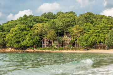 sea with rolling waves and holiday houses in the background at Koh Samet