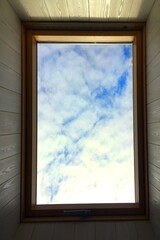 A blue sky with white clouds is visible through the roof window. Template for screen wallpaper, poster, site.