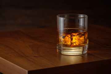 Whiskey on the rocks with ice cubes on wooden table