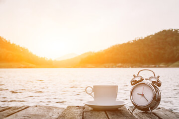 The alarm clock set by the window in the morning beside the coffee cup is used to set the time to...