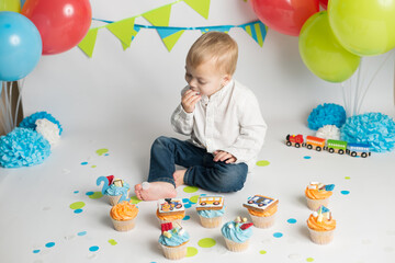 Fototapeta na wymiar Birthday party. little boy eating his holiday cupcakes