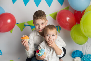 Fototapeta na wymiar Birthday party. brothers eat holiday cupcakes