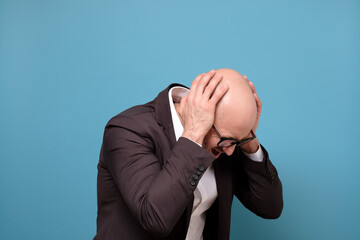 Paranoid mature man covering his ears being annoyed with loud noise. Studio shot