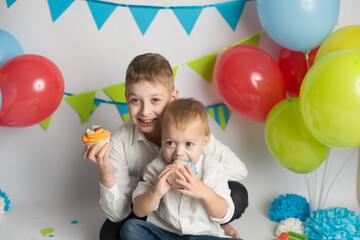 Fototapeta na wymiar Birthday party. brothers eat holiday cupcakes