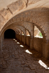 Balcony of an old castle. Arches leading to a dark tunnel end.