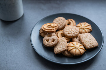 Grey plate with danish cookies and a mug on concrete background.  Close up view.