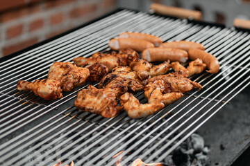 Grilled food. Grilled pork sausage, bacon and vegetables on the grill plate, top view, outdoor. Barbecue, bbq