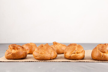 Fresh golden buns from custard dough (Profiteroles) on a light background. Place for text