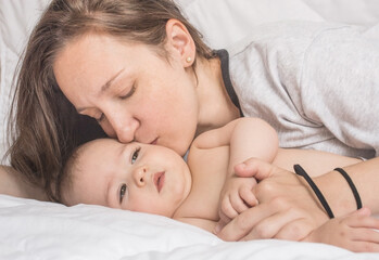 Happy mother playing with sweet little baby boy, white background