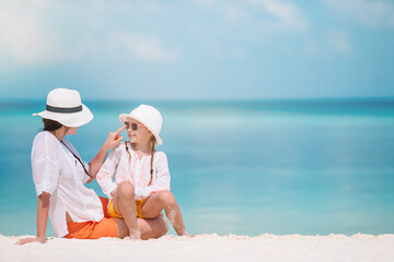 Beautiful mother and daughter at Caribbean beach enjoying summer vacation.