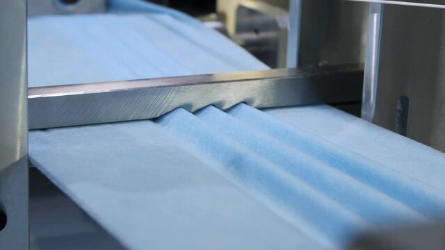 production line makes gofferings on fabric strip for masks