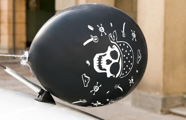 Globo con dibujo pirata colocado en la antena de un automóvil en la calle.