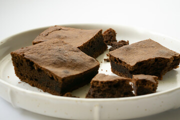 Chocolate brownie sliced into square slices on a white plate.