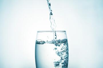 Close up of pouring purified drinking water from a bottle with bubbles and splashes on a white background