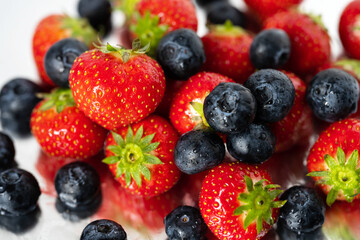 strawberries and blueberries in water drops close up