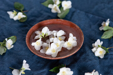 Fototapeta na wymiar White jasmine flowers, clay plate, on a dark blue textile background
