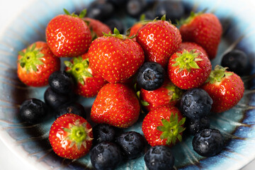 strawberries and blueberries on a blue plate close up