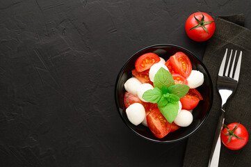 Healthy eating concept. Tasty summer salad with mozzarella and cherry tomatoes. Top view with copy space. Dark slate background.