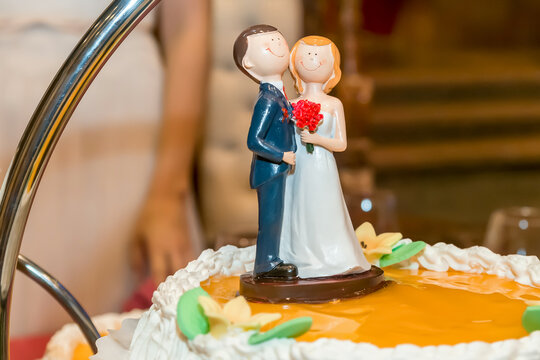 Cara sonriente de la figura de porcelana de la novia junto a la figura del novio en un pastel de novios.