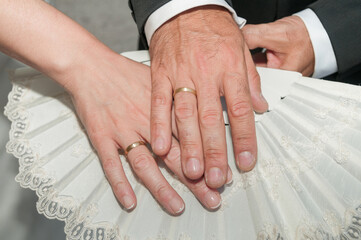 La mano del novio con un anillo de oro junto la mano de la novia también con un anillo y ambas...