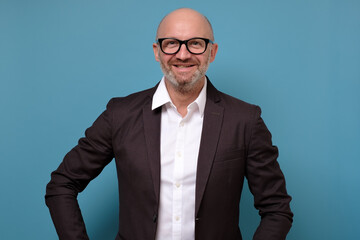 Portrait of smiling man in suit and glasses. Studio shot on blue wall. Positive facial human emotion.