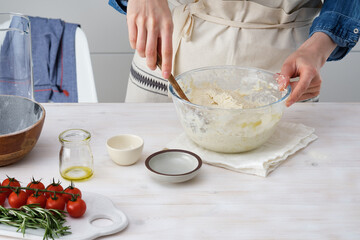 The woman is kneading fresh dough balls in the home. Ingredients for dough: salt, olive oil and fresh herbs.