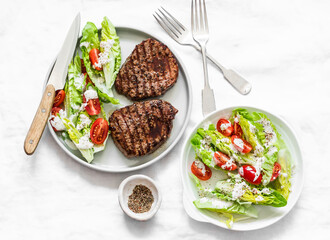 Beef  steak and fresh romaine salad cherry tomatoes yogurt dressing salad on a light background, top view