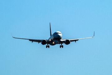 Aircraft with side lights on against a clear blue sky