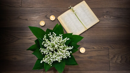 Bouquet of lilies of the valley with green leaves on a wooden table.