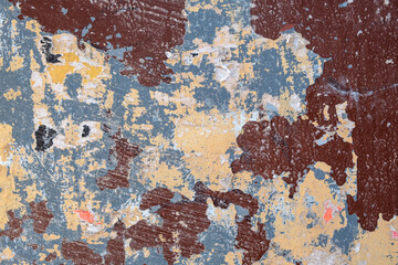 old gray beige wall with spots and stripes, scratches of brown paint with scraps of paper ads. rough surface texture