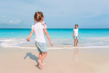 Adorable little girls have a lot of fun on the beach.