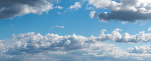Panorama of blue sky with white curly clouds