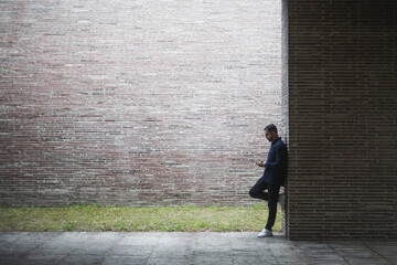 Side view of contemplating man standing by wall