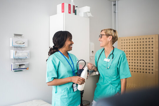 Smiling female pediatricians talking while standing in clinic