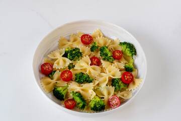 Farfalle pasta bow tie with broccoli and cherry tomatoes. Top view. Flat lay photo.